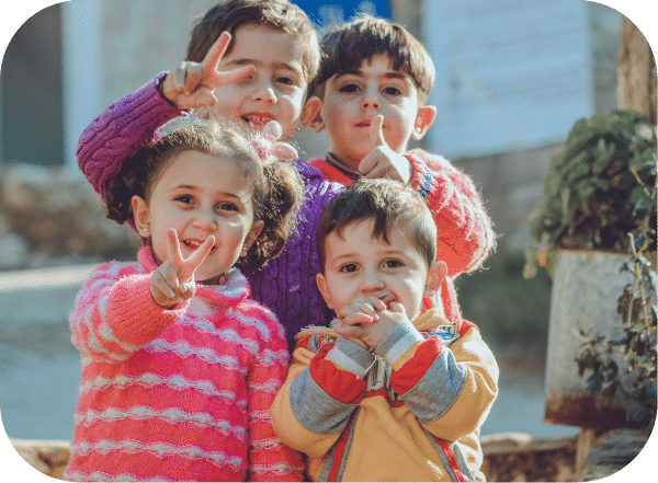 group of 4 children gesturing with signs of positive and peace